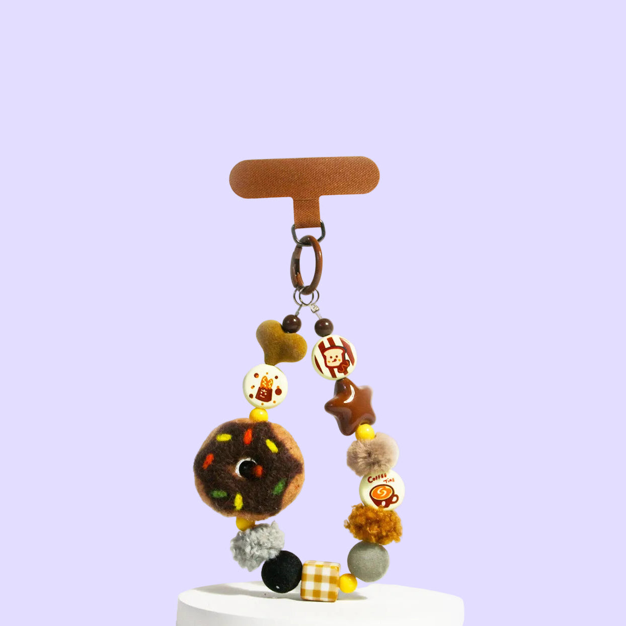 A beaded keychain or bag charm with multiple cartoon and food-themed beads, hanging from a brown T-bar 