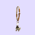 A handmade leather keychain or phone strap charm featuring a stylized cartoon duck character. The strap is made of cream and brown leather with knotted details, and the dangling duck charm is cream and brown with a small orange beak.