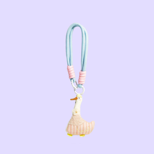 A pastel-colored duck charm keychain or bag clip with a light blue strap, pink ribbed accents, and a cream duck figure with yellow feet